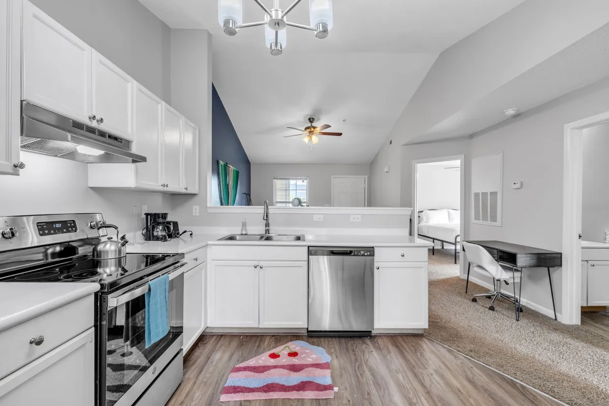 A cozy kitchen interior with stainless steel appliances, a colorful kitchen rug adding warmth, and an open layout ideal for entertaining. The scene suggests spaces for preparing meals, hosting, and casual family gatherings.