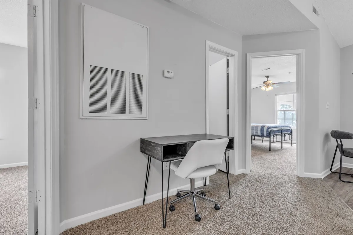 A functional and contemporary space featuring a desk and chair situated near an entrance to the bedroom, with a textured wall adding visual interest. This area offers a spot for catching up on work or planning upcoming activities, further enhancing the versatility of the open-concept layout.