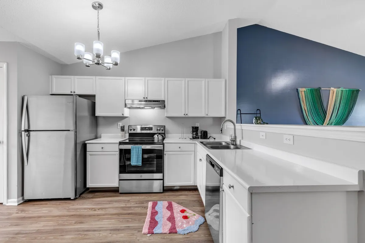 A bright, inviting kitchen featuring stainless steel appliances, crisp white cabinetry, and a colorful decorative bowl on the counter. The space is set up for both cooking and entertaining, with ample counter space and cheerful decor that encourages gathering.