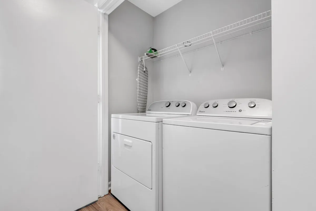 A practical laundry area featuring a modern washing machine and dryer with a convenient shelf above for organizing laundry supplies. The clean, straightforward setup emphasizes ease and functionality for daily living.